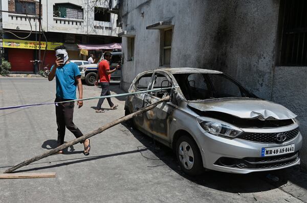 Passerby take photos of a burnt vehicle a day after communal clashes sparked by protests demanding removal of the tomb of 17th-century Muslim Mughal ruler Aurangzeb in Nagpur, India, Tuesday, March 18, 2025. (AP Photo)