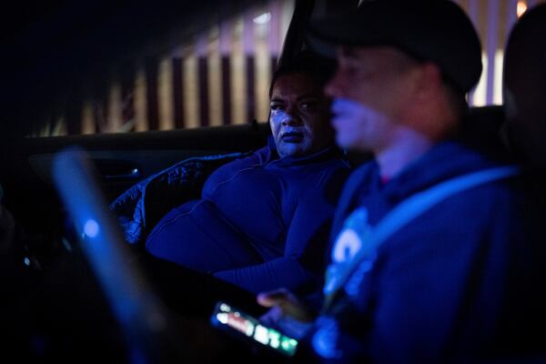 Martha Rosales, left, talks with Cuban migrant Yoandis Delgado as they drive to the Tijuana airport to pick up an arriving migrant who will stay at Rosales' home while waiting an appointment to apply for asylum in the United States through the CBP One app Wednesday, Aug. 28, 2024, in Tijuana, Mexico. (AP Photo/Gregory Bull)