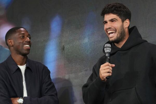 Titleholder Carlos Alcaraz, of Spain, speaks during the draw of French Open tennis tournament while PSG soccer player Ousmane Dembele looks on, Thursday, May 22, 2025 at the Roland Garros stadium in Paris. (AP Photo/Christophe Ena)