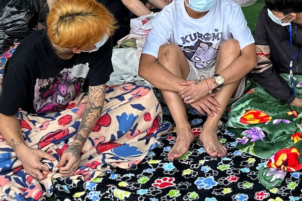 People from China, believed to have been trafficked and forced to work in scam centers, sit with their faces masked while in detention after being released from the centers in Myawaddy district in eastern Myanmar, Wednesday, Feb. 26, 2025. (AP Photo/Chiravuth Rungjamratratsami)