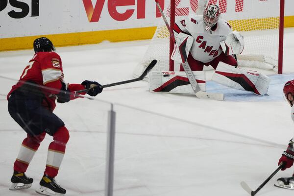 Florida Panthers defenseman Niko Mikkola, left, shoots to score a goal against Carolina Hurricanes goaltender Pyotr Kochetkov, right, during the third period in Game 3 of the NHL hockey Stanley Cup Eastern Conference finals Saturday, May 24, 2025, in Sunrise, Fla. (AP Photo/Lynne Sladky)