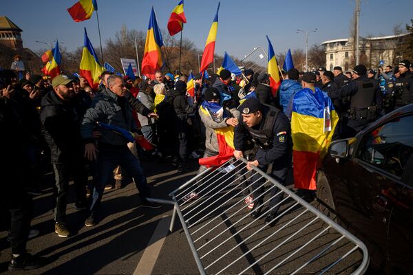 Riot police scuffle with supporters of Calin Georgescu, the winner of Romania's first round of presidential election which the Constitutional Court later annulled, who broke through police lines in front of the government headquarters, in Bucharest, Romania, Monday, Feb. 10, 2025. (AP Photo/Alexandru Dobre)