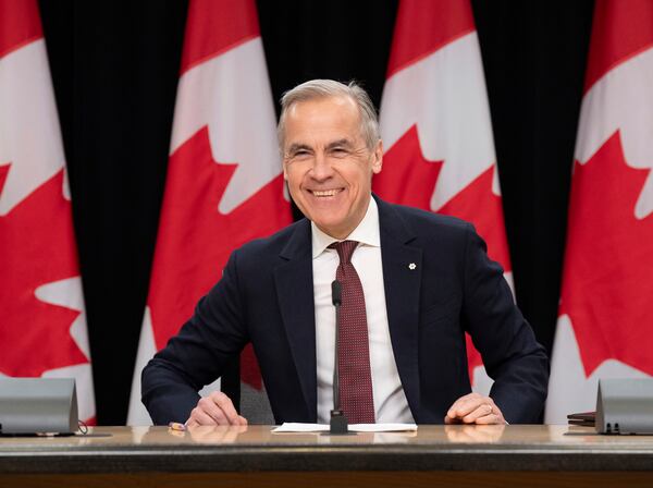 Prime Minister Mark Carney smiles as he takes his seat at his first news conference since winning the federal election, in Ottawa, Friday, May 2, 2025. (Adrian Wyld /The Canadian Press via AP)