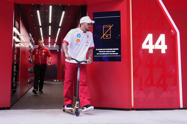 Ferrari driver Lewis Hamilton, of Britain, rides a scooter as he leaves the Ferrari garage ahead of the Formula One Miami Grand Prix auto race, Thursday, May 1, 2025, in Miami Gardens, Fla. (AP Photo/Rebecca Blackwell)