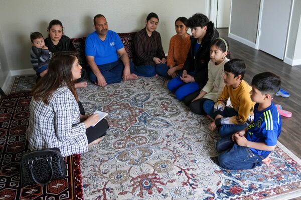 Horia Obaidy, of the No One Left Behind Organization, left, that helps Afghans resettle in the United States, meets with Mohammad Sabor Osmani, in blue, and his family in Rancho Cordova, Calif., Wednesday, March 12, 2025. (AP Photo/Rich Pedroncelli)