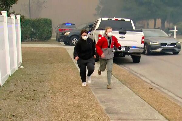 People move from an area where crews work to contain a fire in the Carolina Forest area west of the coastal resort city of Myrtle Beach, S.C., Sunday, March 2, 2025, where residents were ordered to evacuate several neighborhoods. (WMBF-TV via AP)