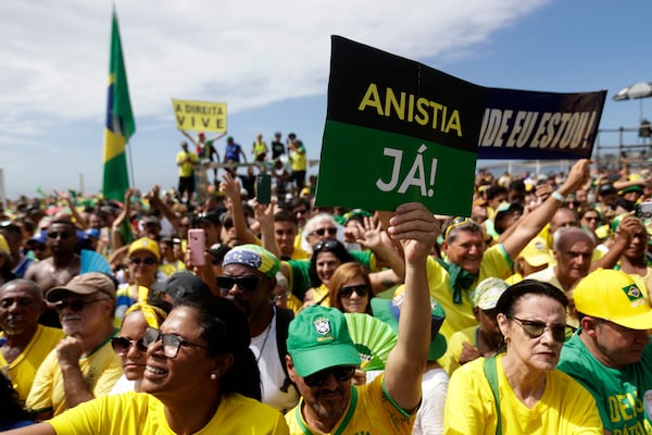 A supporter of former President Jair Bolsonaro holds up a sign that reads in Portuguese "Amnesty Now," during a rally on Copacabana Beach in support of a proposed bill to grant amnesty to those arrested for storming government buildings in an alleged coup attempt in 2023, in Rio de Janeiro, Sunday, March 16, 2025. (AP Photo/Bruna Prado)