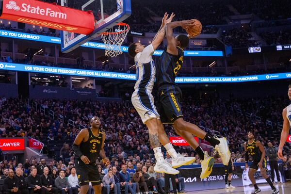 Golden State Warriors' Andrew Wiggins jumps to drunk the ball as Orlando Magic's Cole Anthony tries to block him during an NBA game at the Chase Center in San Francisco on Monday, Feb. 3, 2025. (Dan Hernandez/San Francisco Chronicle via AP)