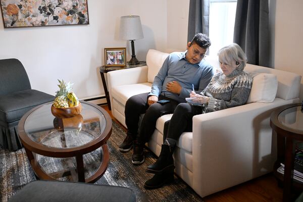 In this Jan. 3, 2025 photo, Rogers Lopez, left, talks with Michele Shackelford, president of the New Milford Refugee Resettlement at his apartment in New Milford, Conn. (AP Photo/Jessica Hill)