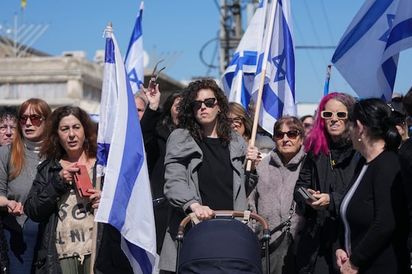 People wave Israeli flags before the funeral of former hostage Oded Lifshitz in Rishon Lezion, central Israel, on Tuesday, Feb. 25, 2025. Lifshitz was abducted by Hamas on Oct. 7, 2023, and his remains were returned from Gaza to Israel last week as part of a ceasefire with Hamas. (AP Photo/Maya Alleruzzo)