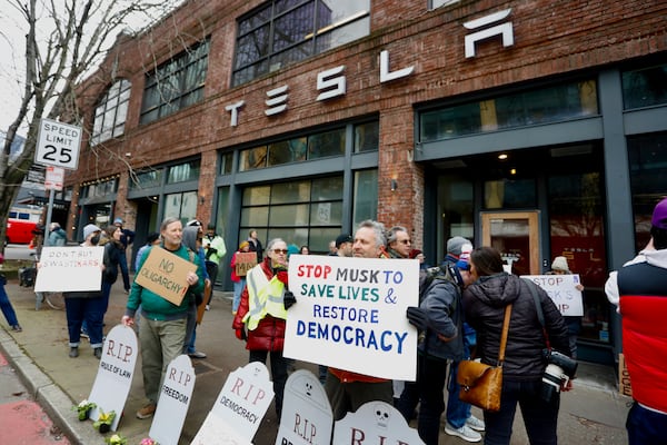 People protesting Elon Musk's actions in the Trump administration hold signs outside a Tesla showroom in Seattle on Thursday, Feb. 13, 2025. (AP Photo/Manuel Valdes)