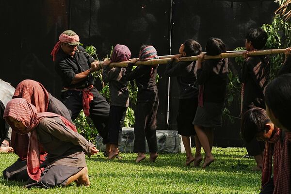 Cambodian students from Royal University of Fine Arts reenact a torture, with children being put on bamboo around their necks by the Khmer Rouge during their reign of terror in the 1970s in an event hosted by the ruling Cambodian People's Party to mark the annual of Remembrance Day at Choeung Ek, a former Khmer Rouge "killing field," on the outskirt of Phnom Penh, Cambodia Tuesday, May 20, 2025. (AP Photo/Heng Sinith)