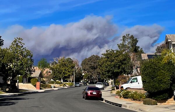 A large plume of smoke caused by the Hughes Fire rises from Castaic Lake as seen from a neighborhood of Santa Clarita, Calif., Wednesday, Jan. 22, 2025. (AP Photo/Marcio Jose Sanchez)