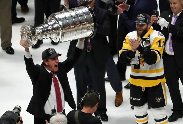 FILE - Pittsburgh Penguins head coach Mike Sullivan hoists the Stanley Cup as Bryan Rust (17) watches after defeating the Nashville Predators 2-0 in Game 6 of the NHL hockey Stanley Cup Final, Sunday, June 11, 2017, in Nashville, Tenn. (AP Photo/Jeff Roberson, file)