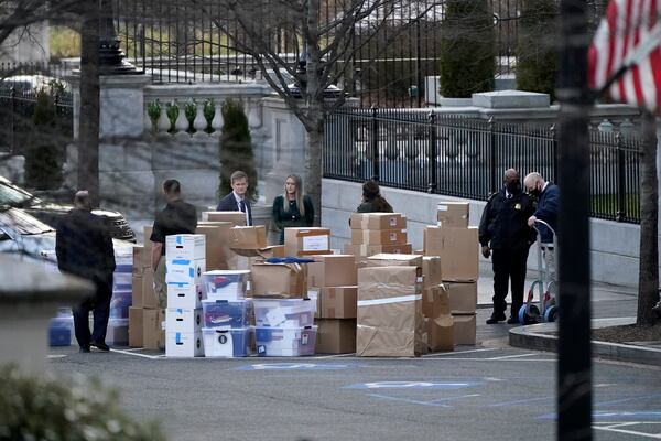 FILE - People wait for a moving van after boxes were moved out of the Eisenhower Executive Office building inside the White House complex, Jan. 14, 2021, in Washington. (AP Photo/Gerald Herbert, File)