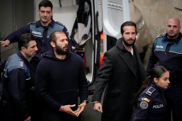 FILE- Police officers escort Andrew Tate, center, handcuffed to his brother Tristan Tate, to the Court of Appeal in Bucharest, Romania, Monday, Feb. 27, 2023. (AP Photo/Andreea Alexandru, File)