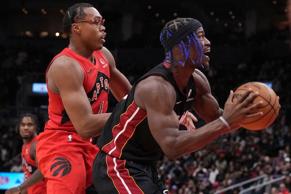 Miami Heat's Jimmy Butler, right, drives to the net against Toronto Raptors' Scottie Barnes, front left, during second -half NBA basketball game action in Toronto, Sunday, Dec. 1, 2024. (Chris Young/The Canadian Press via AP)