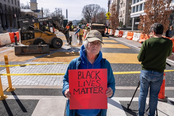 Jessica Sawyer, 77, of Rockville, Md., holds a sign saying "Black Lives Matter," Monday, March 10, 2025, as demolition begins on the Black Lives Matter mural in Washington. "I'm very angry that the Trump administration is forcing the D.C. government to take away something that is so important," says Sawyer. (AP Photo/Jacquelyn Martin)