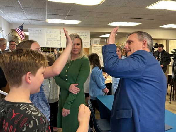 North Dakota Republican Gov. Kelly Armstrong, at right, high-fives a student at Centennial Elementary School in Bismarck, N.D., on Friday, April 25, 2025, after he signed a bill for a "bell-to-bell" cellphone ban for public school K-12 students. At middle is first lady Kjersti Armstrong. (AP Photo/Jack Dura)