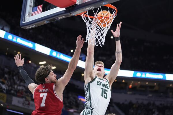 Michigan State center Carson Cooper (15) shoots on Wisconsin forward Carter Gilmore (7) during the first half of an NCAA college basketball game in the semifinals of the Big Ten Conference tournament in Indianapolis, Saturday, March 15, 2025. (AP Photo/Michael Conroy)