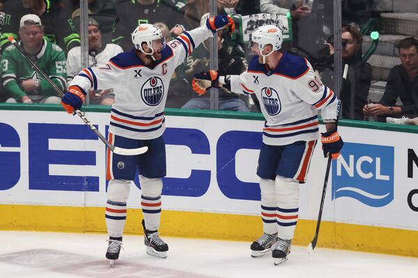 Edmonton Oilers right wing Corey Perry, right, celebrates with center Connor McDavid after scoring during the first period of Game 5 of the Western Conference finals in the NHL hockey Stanley Cup playoffs, Thursday, May 29, 2025, in Dallas. (AP Photo/Gareth Patterson)