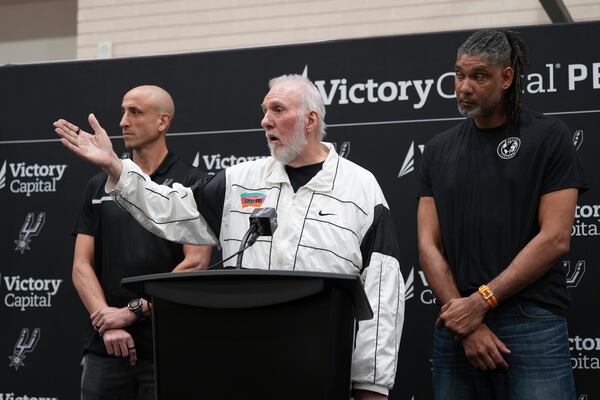 With the help of former players Manu Ginobili, left, and Tim Duncan, right, former San Antonio Spurs head coach Gregg Popovich, center, introduces Mitch Johnson as the new head coach of the San Antonio Spurs NBA basketball team, in San Antonio, Monday, May 5, 2025. (AP Photo/Eric Gay)