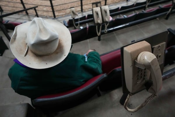 Telephones are visible along the seating area in the auction arena as a buyer watches a sale at the Oklahoma National Stockyards Tuesday, Jan. 14, 2025, in Oklahoma City. (AP Photo/Julio Cortez)