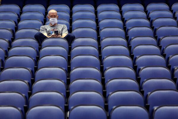 FILE - Mike Lemcke, from Richmond, Va., sits in an empty Greensboro Coliseum after the NCAA college basketball games at the Atlantic Coast Conference tournament were canceled due to concerns about the coronavirus, Thursday, March 12, 2020, in Greensboro, N.C. (AP Photo/Ben McKeown, File)