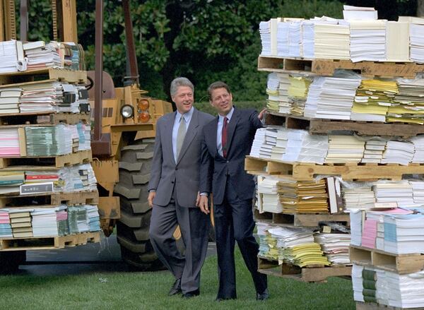 FILE - President Bill Clinton, left, and Vice President Al Gore walk past two forklifts carrying reams of federal rules and regulations prior to making their reinventing government announcement, Sept. 7, 1993, at the White House in Washington. The plan unveiled plans to cut, consolidate and reshape the government, saving $108 billion by the century's end. (AP Photo/J. Scott Applewhite, File)