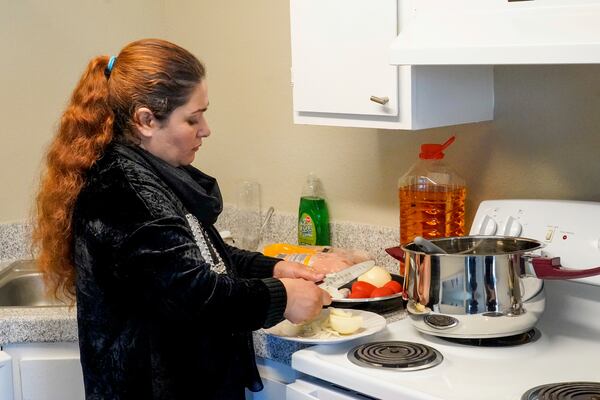 Noria Sdeqi prepares lunch for her family in their new home provided by the No One Left Behind Organization, in Rancho Cordova, Calif., Wednesday, March 12, 2025. (AP Photo/Rich Pedroncelli)