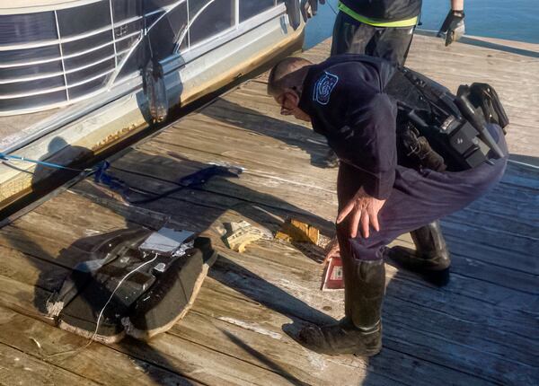 This image provided by Dean Naujoks shows a law enforcement officer looking at debris recovered from the Potomoc River on a dock on Daingerfield Island south of Ronald Reagan Washington National Airport in Alexandria, Va., Thursday, Jan. 30, 2025 (Dean Naujoks via AP)