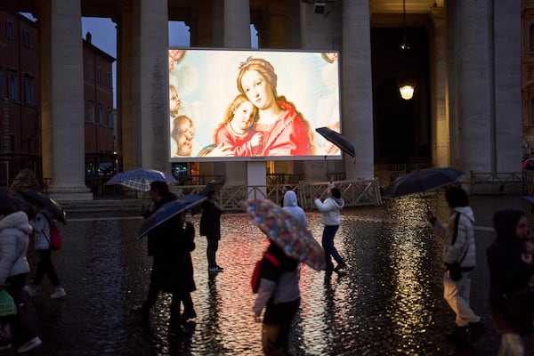 People shelter against the rain as they follow a live broadcasted Rosary prayer for Pope Francis, in St. Peter's Square at the Vatican, Wednesday, March 12, 2025. (AP Photo/Francisco Seco)