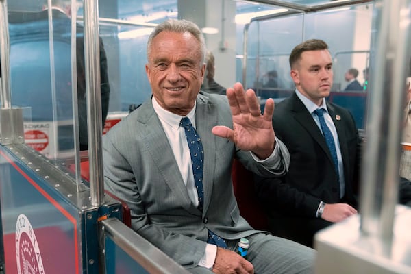 Robert F. Kennedy Jr., President-elect Donald Trump's nominee to be Secretary of Health and Human Services, waves to the media as he rides the train to go to meet with Sen. John Thune, R-S.D. at the Capitol in Washington, Tuesday, Dec. 17, 2024. (AP Photo/Jose Luis Magana)