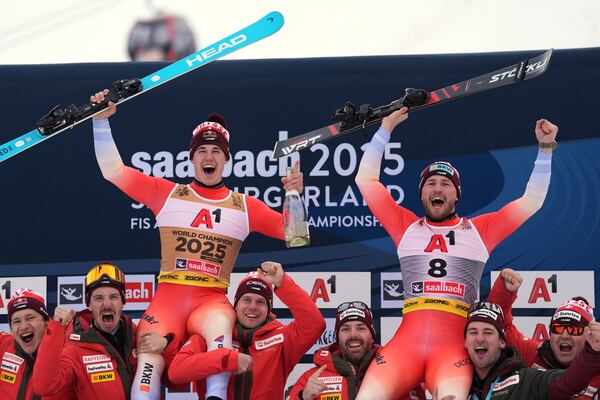 Gold medalist in a men's downhill race Switzerland's Franjo von Allmen, left, and bronze medalist Switzerland's Alexis Monney, celebrate with the team, at the Alpine Ski World Championships, in Saalbach-Hinterglemm, Austria, Sunday, Feb. 9, 2025. (AP Photo/Giovanni Auletta)