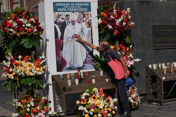 A parishioner touches an image of Pope Fransisco during a prayer service for his health outside of the Basilica of Guadalupe in Mexico City, Monday, Feb. 24, 2025. (AP Photo/Marco Ugarte)