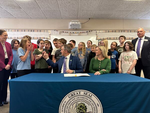 Students react as North Dakota Republican Gov. Kelly Armstrong hands a pen to a girl after he signed a bill for a "bell-to-bell" cellphone ban for public school K-12 students on Friday, April 25, 2025, at Centennial Elementary School in Bismarck, N.D. To the right of the governor is first lady Kjersti Armstrong. Republican Sen. Michelle Axtman is at left. Republican Rep. Jim Jonas is at right. (AP Photo/Jack Dura)