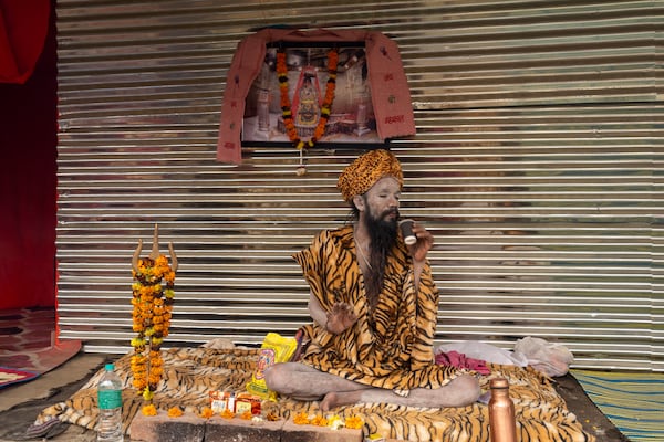 A Hindu holy man sips tea at his makeshift living quarters at the confluence of the Ganges, the Yamuna and the mythical Saraswati rivers, a day before the official beginning of the 45-day-long Maha Kumbh festival, in Prayagraj, India, Sunday, Jan. 12, 2025. (AP Photo/Ashwini Bhatia)