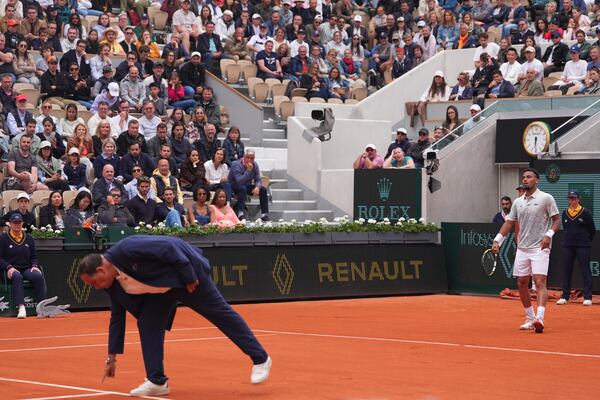 The chair umpire checks a mark on the clay as France's Arthur Fils looks on, during his first round match of the French Tennis Open against Chile's Nicolas Jarry, at the Roland-Garros stadium, in Paris, Monday, May 26, 2025. (AP Photo/Lindsey Wasson)