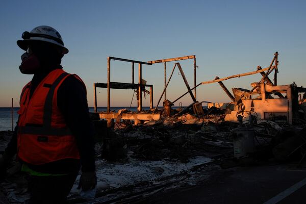 A worker walks past a fire-ravaged beachfront property in the aftermath of the Palisades Fire Monday, Jan. 13, 2025 in Malibu, Calif. (AP Photo/John Locher)