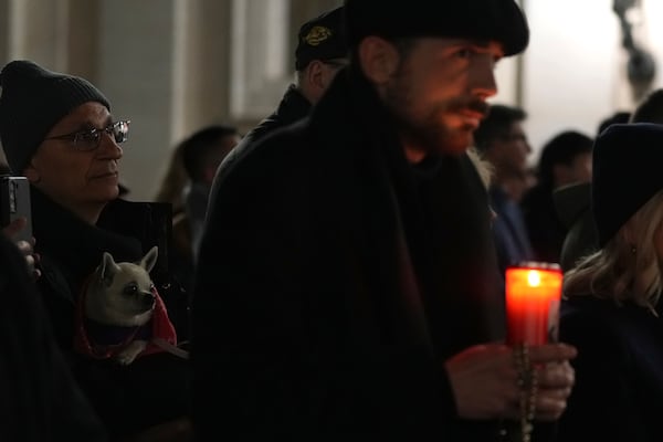 A man holds a little dog during a rosary prayer for Pope Francis' health in St. Peter's Square at the Vatican, Wednesday, March 5, 2025. (AP Photo/Alessandra Tarantino)