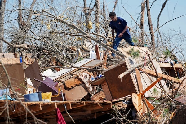 Family friend Trey Bridges, 16, climbs a mountain of tornado debris to help the Blansett family recover items not destroyed by Saturday's tornado, Sunday, March 16, 2025, in Tylertown, Miss. (AP Photo/Rogelio V. Solis)