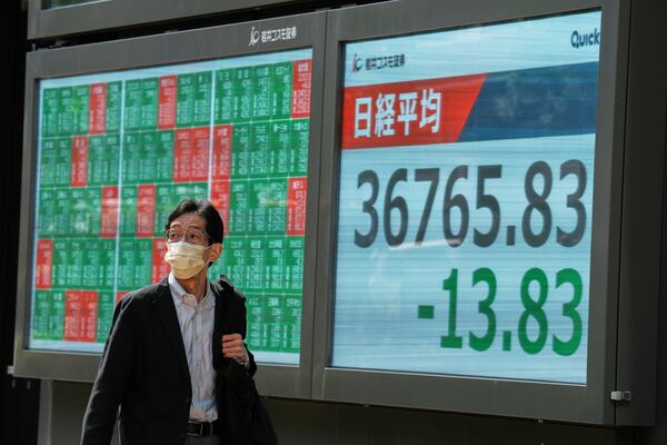 A person walks in front of an electronic stock board showing Japan's Nikkei index at a securities firm Thursday, May 8, 2025, in Tokyo. (AP Photo/Eugene Hoshiko)
