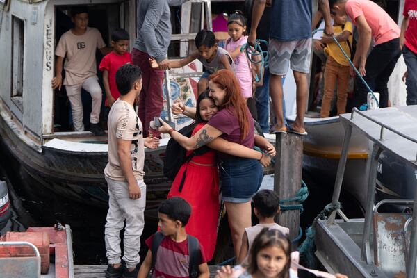 A girl embraces biologist Tatyanna Mariúcha, head of the Emilio Goeldi Museum's scientific base, as children arrive at the station in the Caxiuana National Forest in Para state, Brazil, Friday, March 21, 2025. (AP Photo/Jorge Saenz)