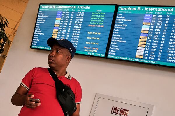A passenger waits near an arrivals board at Newark Liberty International Airport, in New Jersey, Friday, May 23, 2025. (AP Photo/Richard Drew)