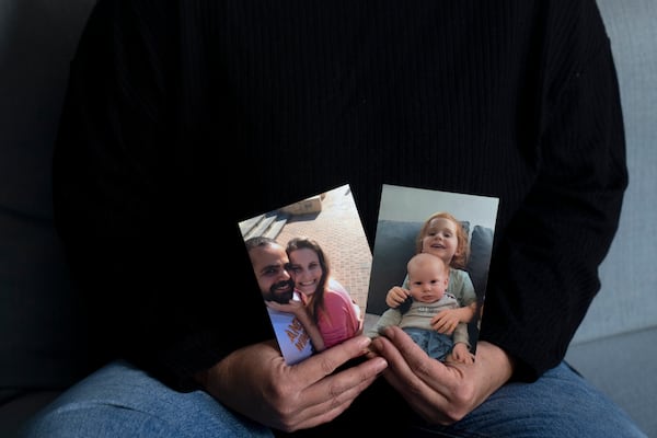 Yifat Zailer shows photos of her cousin, Shiri Bibas, center, her husband Yarden, left, and their sons Ariel, top right, and Kfir, who are being held hostage by Hamas militants in the Gaza Strip, at home in Herziliyya, Israel, on Wednesday, Jan. 15, 2025. (AP Photo/Maya Alleruzzo)