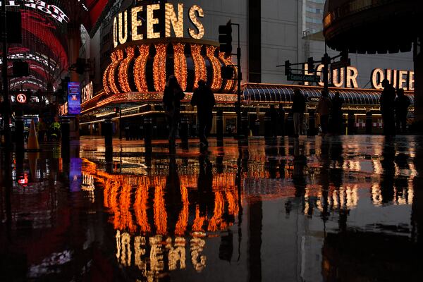 People walk along Fremont Street in the rain Thursday, Feb. 13, 2025, in Las Vegas. (AP Photo/John Locher)