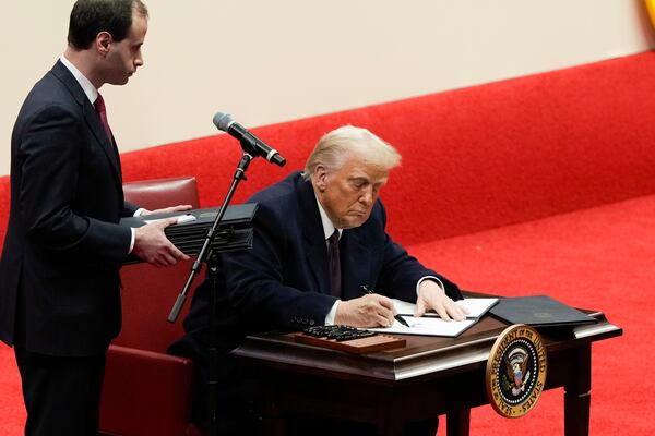 President Donald Trump signs an executive order at an indoor Presidential Inauguration parade event in Washington, Monday, Jan. 20, 2025. (AP Photo/Susan Walsh)