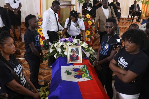 A framed photo of journalist Marckendy Natoux, who was killed by gang members on Christmas Eve while covering the reopening of a hospital, adorns a coffin that contain his remains as friends as family stand vigil during his funeral, in Port-au-Prince, Haiti, Saturday, Jan. 18, 2025.(AP Photo/Odelyn Joseph)