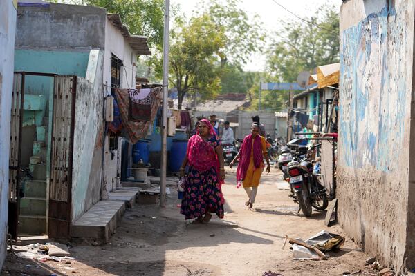 People walk through buildings in Vanzara Vas, a low-income neighborhood, in Ahmedabad, India, Wednesday, April 2, 2025. (AP Photo/Ajit Solanki)