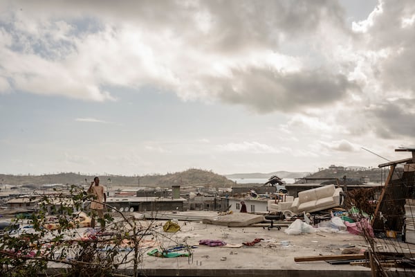 A man stands on his roof in the Kaweni slum on the outskirts of Mamoudzou in the French Indian Ocean island of Mayotte, Thursday, Dec. 19, 2024, after Cyclone Chido. (AP Photo/Adrienne Surprenant)